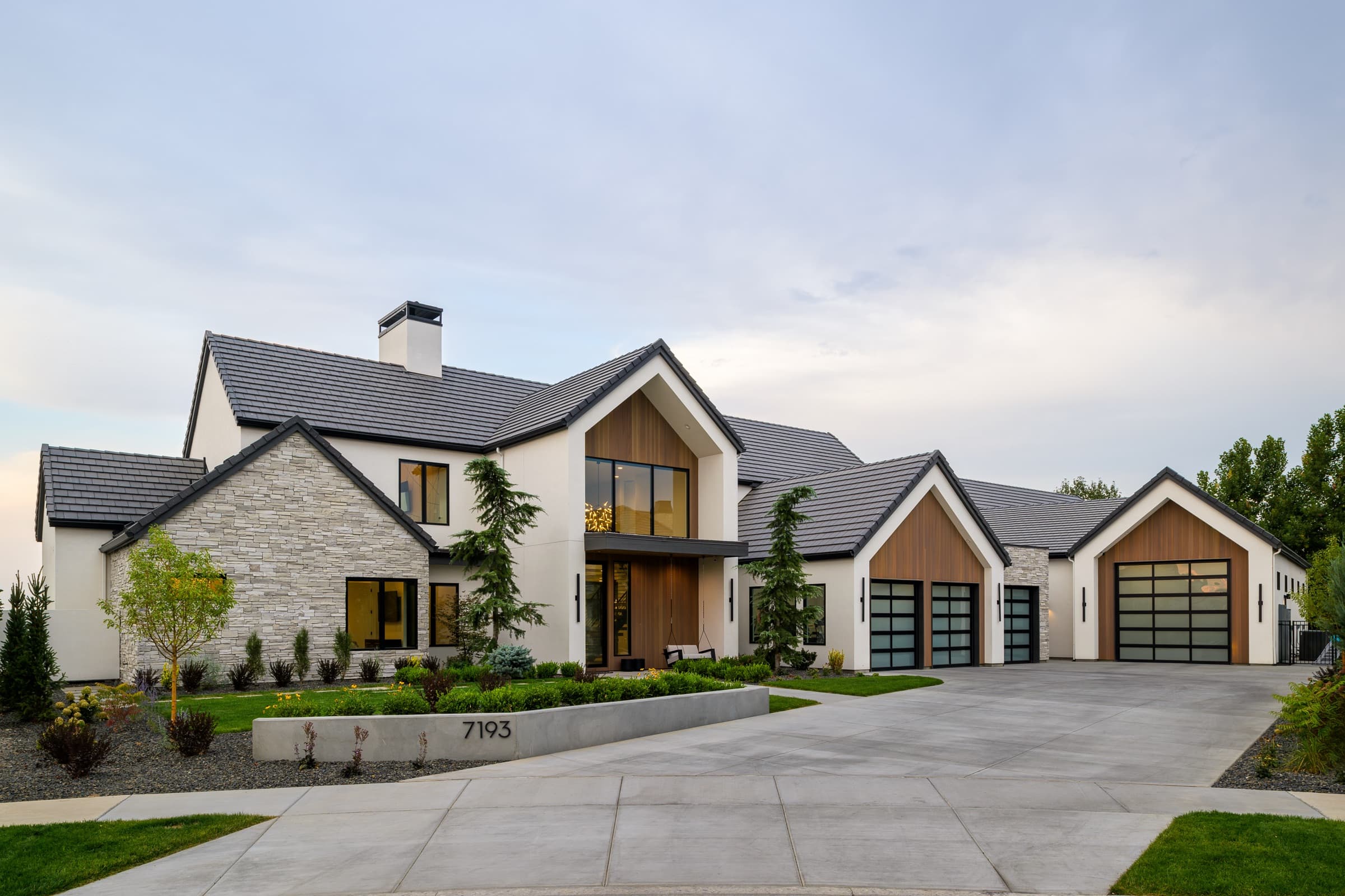 Spurwing custom home at dusk — stone, stucco, and cedar gables